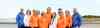 Gruppenfoto des Teams von Schulbegleitung Westküste auf einer Promenade am Strand mit den neuen Kapuzenpullovern in blau, weiß und orange.