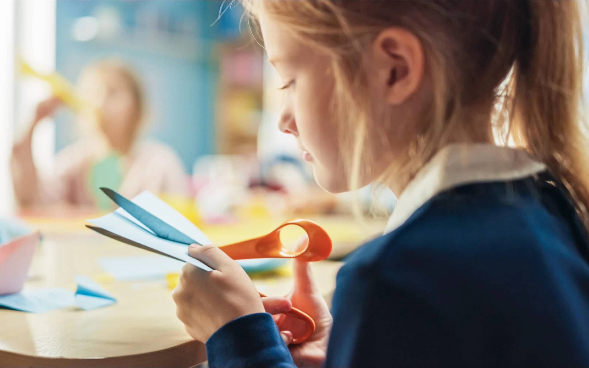 Ein Mädchen schneidet etwas mit einer Bastelschere aus.