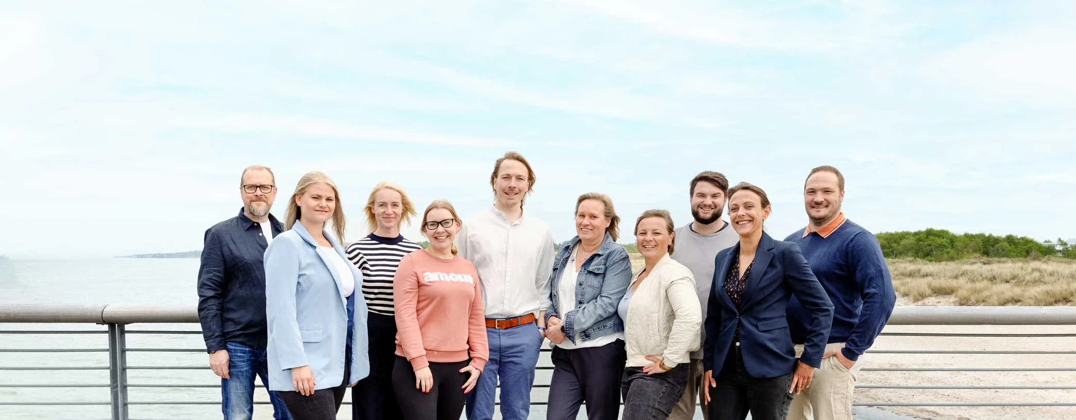 Gruppenfoto des Teams von Schulbegleitung Westküste auf einer Promenade am Strand.