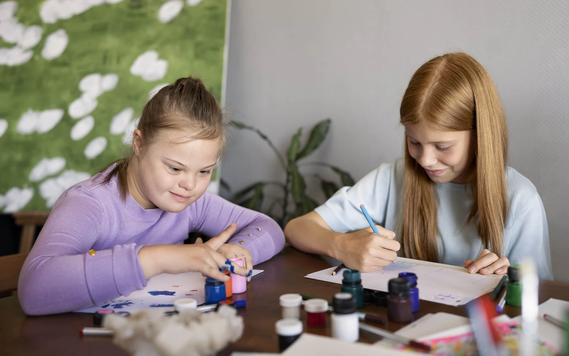 Zwei Kinder sitzen zusammen und malen etwas.